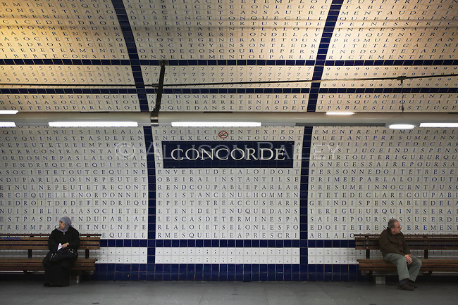 Man and woman facing opposite directions with French constitution in tile on the wall, Concorde Metro station, line, 12 platform, Paris, France